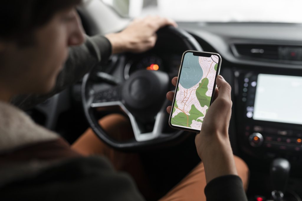 Waze ou Google Maps? Qual o melhor para guiar as sua viagens? feche a mao segurando o smartphone com o mapa