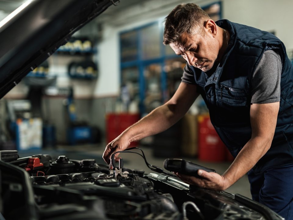 Dicas para Economizar na Manutenção e Reparos do seu Veículo auto mechanic using diagnostic tool while checking car battery voltage workshop 1