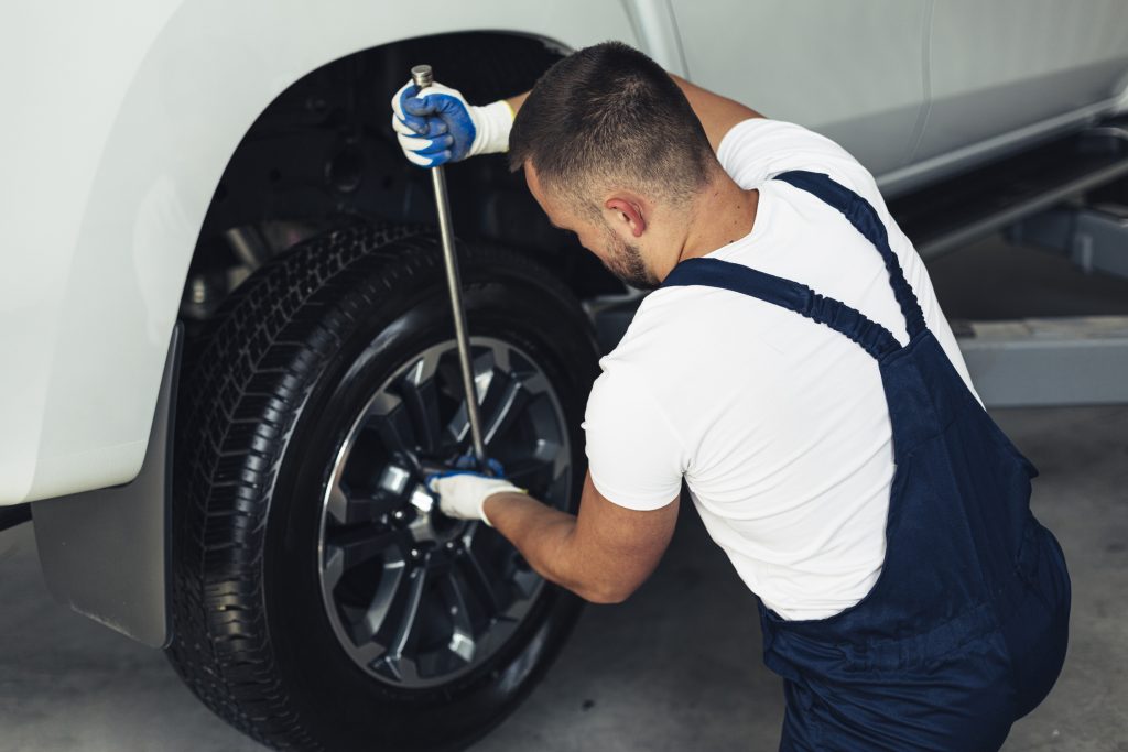 Como cuidar das rodas do seu carro para mantê-las sempre brihnates mecanico masculino de alto angulo mudando as rodas de carro