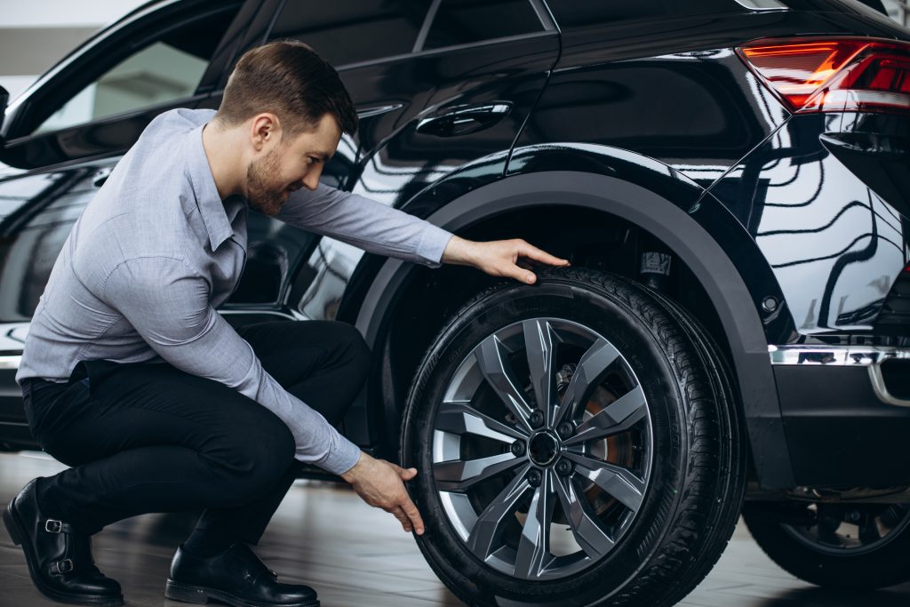Envelopamento de Rodas: Transforme o Visual do seu Veículo com Estilo e Proteção homem escolhendo um carro e verificando os pneus